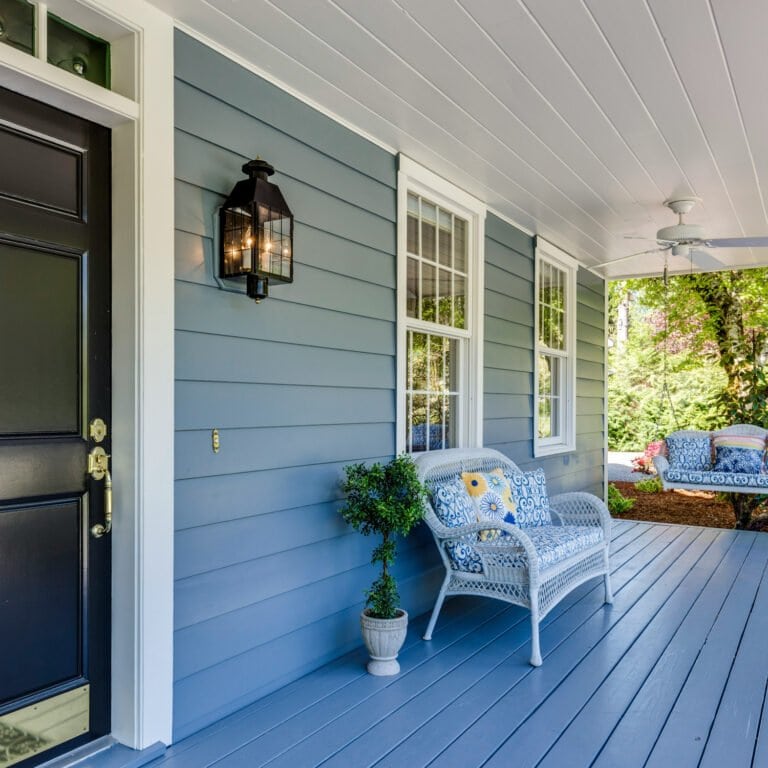 Porche exterior de una casa estilo americano, con paredes en color gris azulado