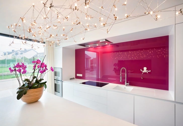 Vidrio lacado rosa en la pared principal de una cocina blanca y moderna